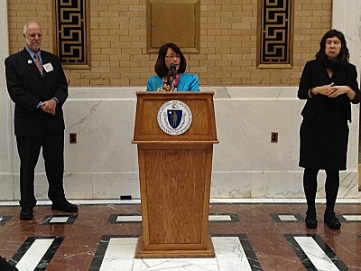 Lisa Wong of the Massachusetts Cultural Council speaking at a podiem flanked by Charles Washburn of VSA Massachusetts and an ASL-interpretor